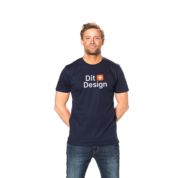 Mand i mørk t-shirt med teksten "Dit Design" står smilende med hænderne bag ryggen i en neutral, lys baggrund. Han bærer også jeans.