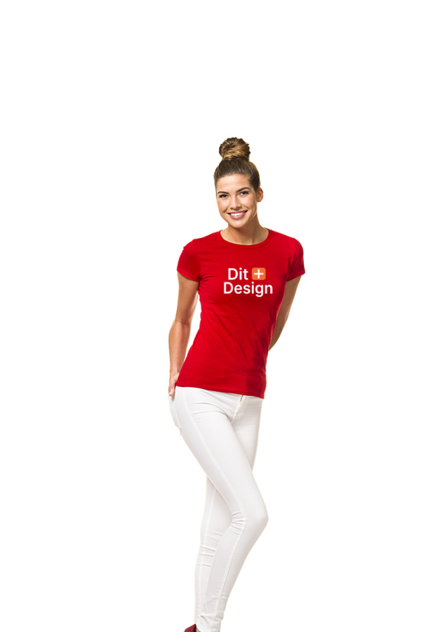 Kvinde står smilende i rød T-shirt med teksten "Dit Design", hænderne bag ryggen, iført hvide bukser. Ren hvid baggrund.
