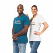 To personer står smilende mod kameraet. Manden bærer en blå T-shirt, kvinden en hvid, begge med teksten "Dit Design". De poserer selvsikkert mod en hvid baggrund.