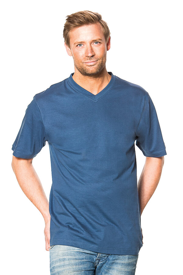 Klassisk V-hals Økologisk harbour En mand iklædt en blå t-shirt står med hænderne i lommerne og kigger direkte fremad. Baggrunden er hvid, hvilket fremhæver mandens tøj.