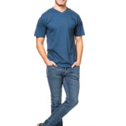 En mand står med hænderne i lommerne og iført en blå T-shirt og jeans. Han står afslappet i et studie mod en hvid baggrund. Ingen tekst til stede.