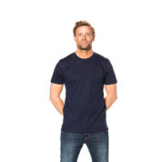 Mand står stille, iført mørkeblå t-shirt og jeans, med hænderne bag ryggen, mod hvid baggrund.