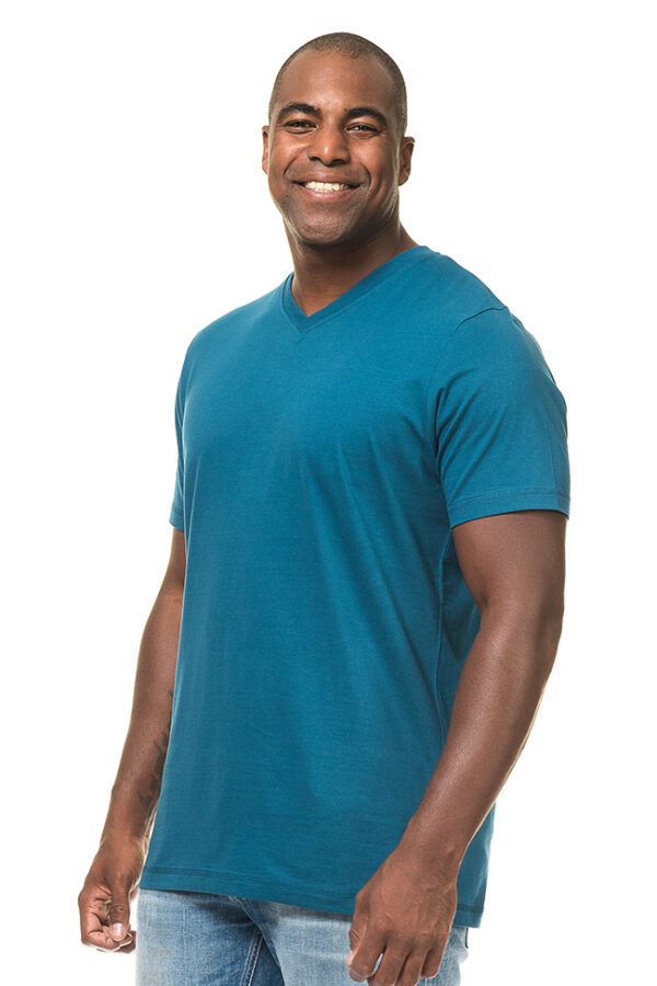 Uni Fashion V-neck Økologisk blue En mand i en blå T-shirt smiler, mens han står oprejst mod en hvid baggrund.