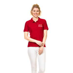 Kvinde i rød polo-shirt med teksten "Dit Design" står afslappet og smiler. Hun bærer hvide bukser, placeret på en hvid baggrund.