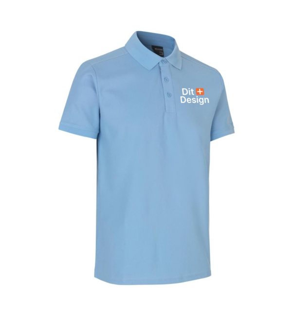Lyseblå poloshirt står oprejst. Den har korte ærmer og en krave med knapper. På brystet er teksten "The Open" ved siden af et logo. Baggrunden er hvid.