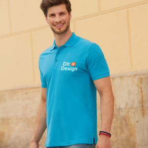Mand iført en lyseblå polo med teksten "Dit Design" går foran en beige murstensvæg, med et venligt smil. Han bærer jeans og armbånd på håndleddet.