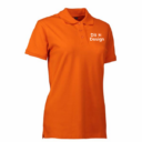 Orange polo-shirt står til venstre; teksten "She is Orange" er trykt i hvidt på brystet. Baggrunden er hvid og neutral.