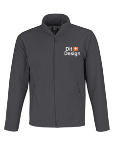 Jakke med lynlås står opret; "Dit Design" tekst til højre for lynlåsen. En simpel grå baggrund fremhæver jakken.