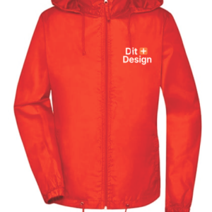 Rød jakke med lynlås foran og hætte, står oprejst. Tekst på brystet: "Dit Design" med et lille kors ved siden af. Enkel baggrund.