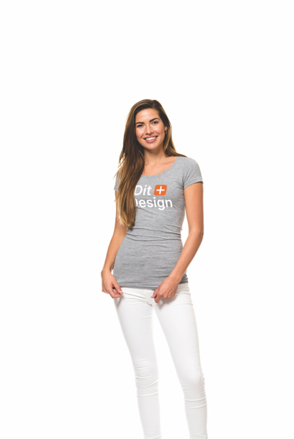 Kvinde står smilende iført grå T-shirt med teksten "Dit Design" og hvide bukser, i neutral, hvid baggrund.