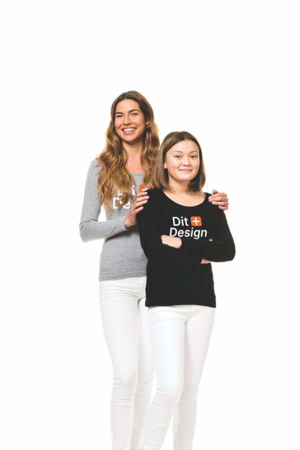 Women & Women - Design 1 To kvinder står sammen; den ene holder den anden på skuldrene. De smiler i et lyst rum. Den ene har en sort bluse med teksten "Stay Unique".