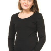 En person iført en sort langærmet trøje står foran en hvid baggrund og smiler let, med armene afslappet foran.