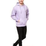 En mand i en lilla hættetrøje og sorte bukser går og smiler. Han har hænderne i lommerne og bærer sorte sneakers. Baggrunden er helt hvid.
