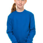 En pige med rødt hår og blå sweater står med hænderne foldet foran sig i en neutral, hvid baggrund.