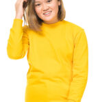 En person iført en gul sweatshirt rører ved sit hår og smiler. Baggrunden er hvid og minimalistisk.