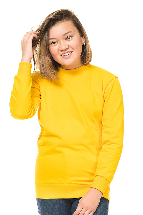 Kraftig Heavy Sweatshirt gul En person iført en gul sweatshirt rører ved sit hår og smiler. Baggrunden er hvid og minimalistisk.