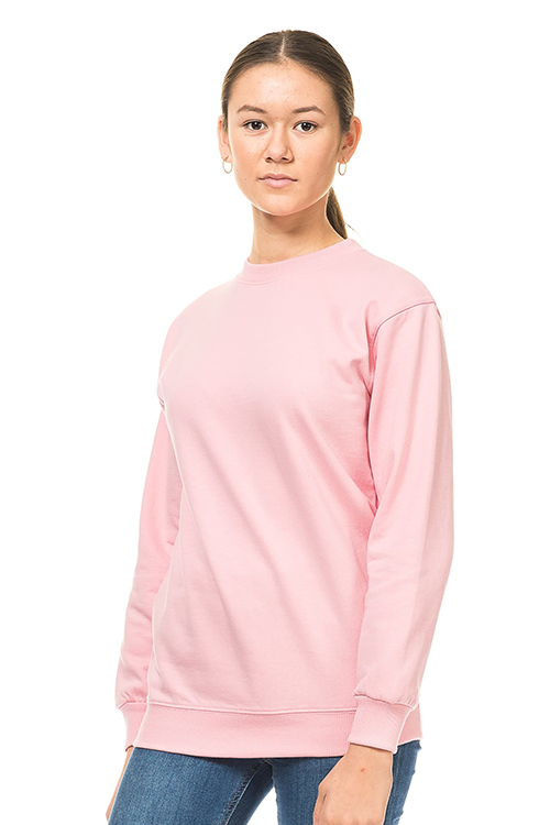 Kraftig Heavy Sweatshirt lyserød En person iført en lyserød sweatshirt står oprejst mod en hvid baggrund, ser direkte fremad og har hænderne ved siden. Personen har håret samlet i en lav hestehale og bærer øreringe.