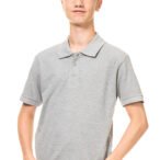 En ung mand har hænderne i lommerne, iført en grå poloshirt i et lyst, enkelt studieopstilling.
