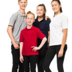 Fire unge personer poserer sammen, iført farverige polo shirts og sorte bukser, står på en hvid baggrund. Ingen tekst ses i billedet.