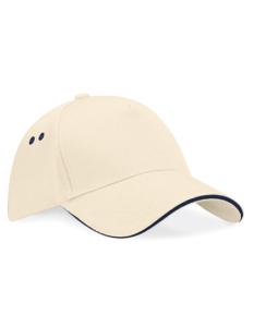 Beige kasket med buet skygge og sort kant, to ventilationshuller på hver side, ligger på en hvid overflade.
