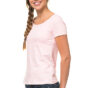 En kvinde med fletning og lyserød t-shirt smiler mod kameraet. Hun står i profil i et lyst studie iført mørke jeans.