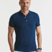 Mand iført blå poloshirt, står oprejst med hænderne i lommerne. Baggrunden er neutral og lysefarvet.