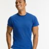 Mand i blå T-shirt smilende, står i hvidt rum med neutrale, minimalistiske baggrund.