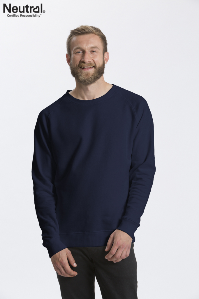 En mand med skæg og kort hår smiler, iført en mørkeblå sweatshirt og sorte bukser. I øverste venstre hjørne er teksten: "Neutral® Certified Responsibility™." Baggrunden er hvid.