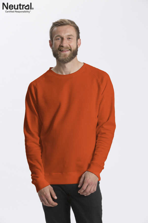 O63001_M_ORAN Mand iført en orange sweatshirt smiler i et studie med en hvid baggrund. På billedets øverste venstre hjørne står der "Neutral Certified Responsibility".