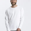 Mand med skæg og kort hår iført en hvid sweatshirt og sorte bukser står smilende mod en hvid baggrund. Tekst: "Neutral Certified Responsibility™".