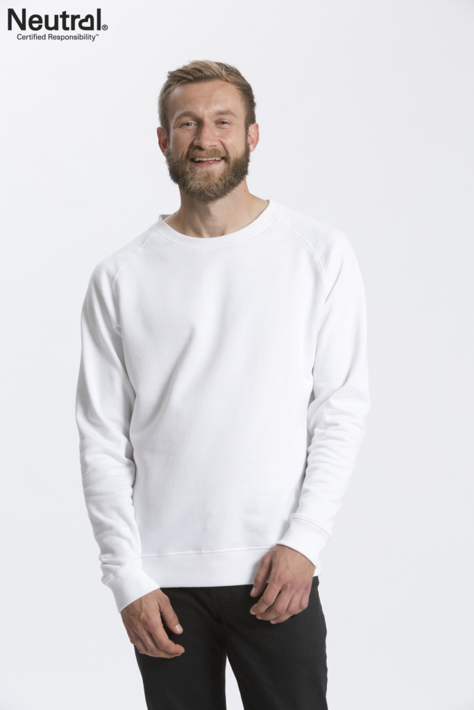 Mand med skæg og kort hår iført en hvid sweatshirt og sorte bukser står smilende mod en hvid baggrund. Tekst: "Neutral Certified Responsibility™".