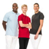 Tre personer står sammen og smiler, iført farverige poloshirts (lyseblå, rød, mørkegrå) og hvide bukser på en hvid baggrund. Den unge person i midten har krydsede arme.