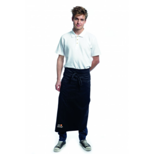 En person står med hænderne i lommerne, iført en hvid t-shirt og sort forklæde, mod en hvid baggrund.