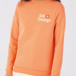 Trøje i orange bæres af en person, tekst "Dit Design" på trøjen. Personen står i et neutralt, lyst rum, iført lyse bukser.