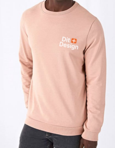 Trøje med teksten "Dit + Design" på brystet bæres af en person, der står mod en lys baggrund og har mørke bukser på.