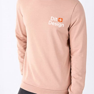 Trøje med teksten "Dit + Design" på brystet bæres af en person, der står mod en lys baggrund og har mørke bukser på.