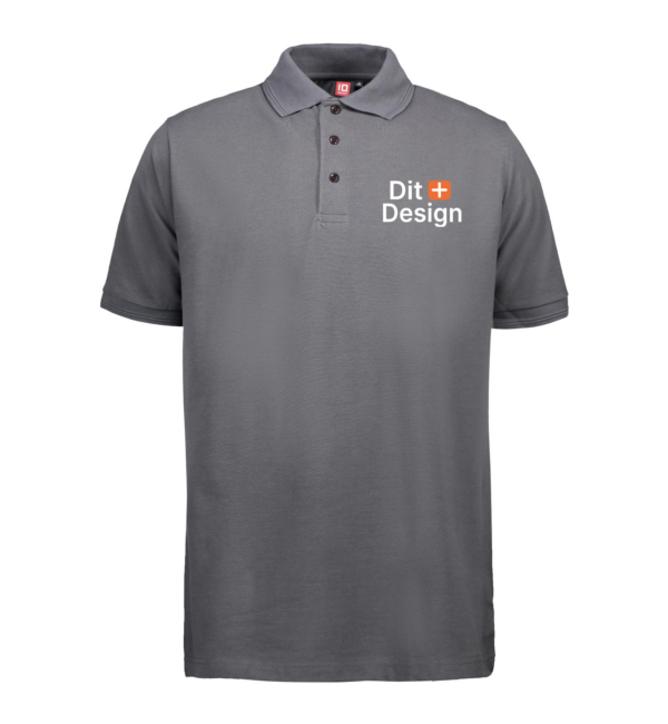 Grå poloshirt vises stående i neutrale omgivelser. Teksten "Dit Design" med et orange plustegn er trykt på venstre bryst.