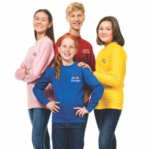 Fire unge personer står sammen og smiler; to piger og en dreng i farverige sweatere, tekst "Dit Design" på brystet. Baggrund er hvid og minimalistisk.