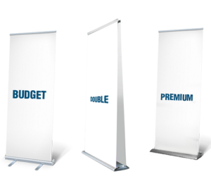 Tre reklamebannere står ved siden af hinanden med tekst på hvert: "BUDGET" på det venstre banner, "DOUBLE" på det midterste, og "PREMIUM" på det højre. Baggrund er grå med skygger.