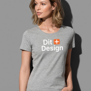 Kvinde iført en grå T-shirt står og kigger til siden. T-shirten har teksten "Dit + Design" trykt på forsiden. Baggrunden er ensfarvet grå.