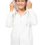 En person i en hvid hættetrøje holder i hættens snore og smiler, iført blå jeans, står foran en hvid baggrund.