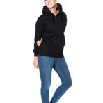 En person står i afslappet position iført en sort hættetrøje og blå jeans på en hvid baggrund. Vedkommende har den ene hånd i lommen og smiler.