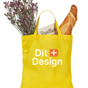 En gul stofpose indeholder en buket lavendel, en avis med teksten "Frankfurter" og en baguette. Posen har teksten "Dit Design" trykt på forsiden.