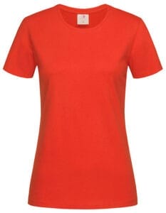 En rød T-shirt hænger frit med en rund hals og kort ærmer. Øverst er der en hvid etiket med en lille tekst. Baggrunden er ensfarvet hvid.
