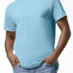 En person iført en lyseblå T-shirt står med hænderne stukket i lommerne på et par blå jeans. Baggrunden er en simpel, hvid væg.