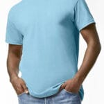 En person iført en lyseblå T-shirt står med hænderne stukket i lommerne på et par blå jeans. Baggrunden er en simpel, hvid væg.