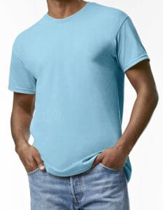 En person iført en lyseblå T-shirt står med hænderne stukket i lommerne på et par blå jeans. Baggrunden er en simpel, hvid væg.