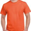 En person iført en orange t-shirt står med hænderne i bukselommerne. T-shirten er ensfarvet, og personen har kort, lyst hår. Personens ansigt er ikke fuldt synligt.