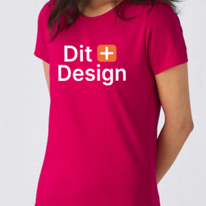 Kvinde iført en pink T-shirt med teksten "Dit Design" i hvid skrift og en lille orange stjerne-ikon. Baggrunden er lys og enkel.