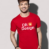 Mand står og smiler iført en rød t-shirt med teksten "Dit Design" i hvid og orange. Han er i et neutralt, gråt rum uden andre synlige elementer.